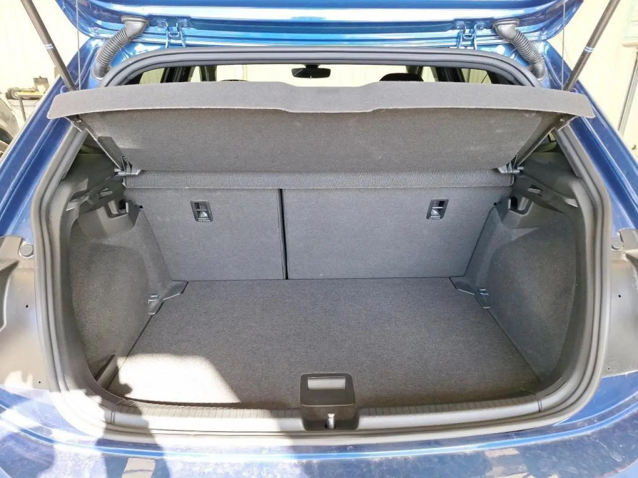 Coffre ouvert vu de l'arrière d'une Volkswagen Polo TSI 95 R-Line bleu récif avec espace de chargement vide.