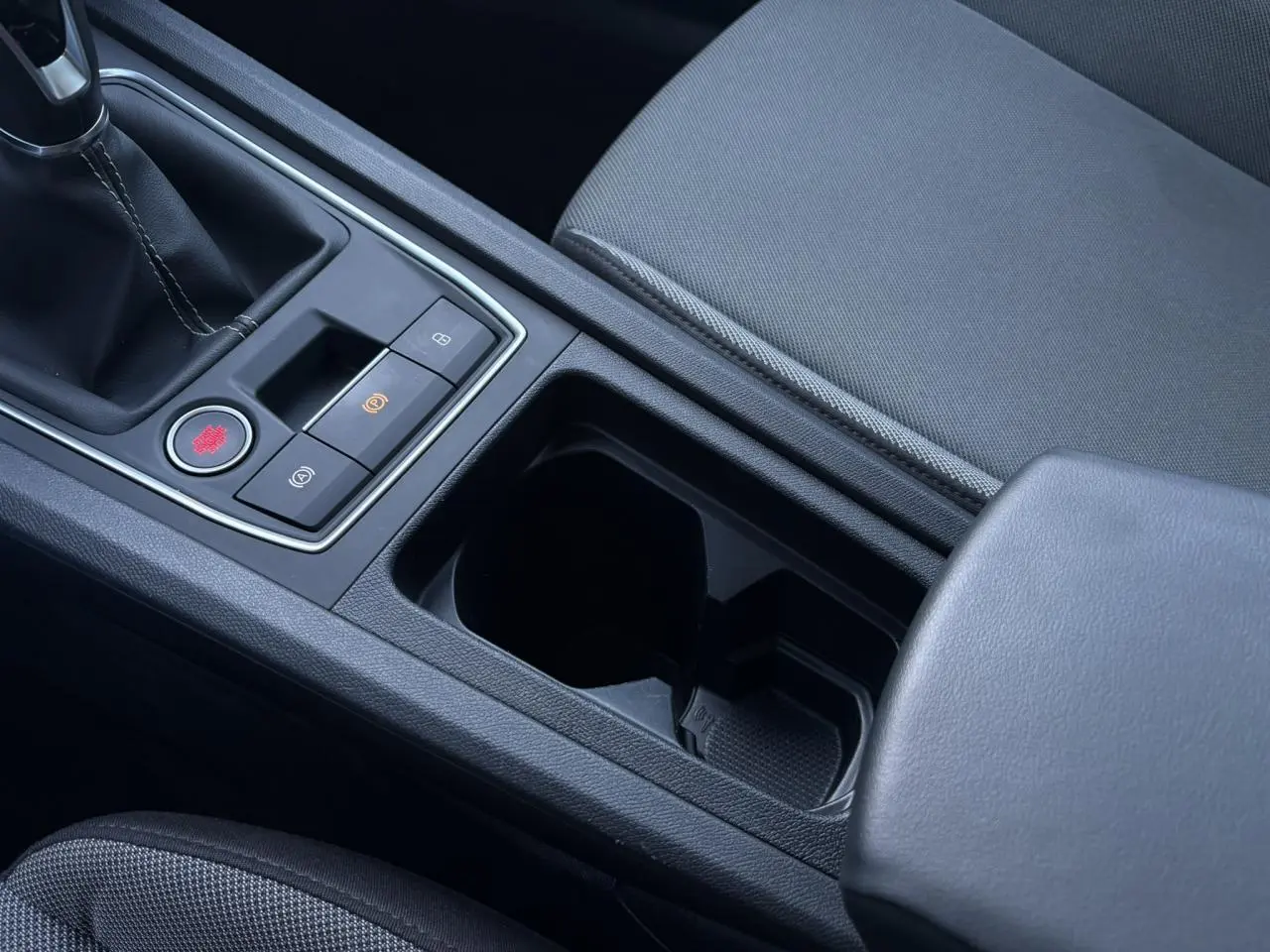 Gros plan sur la console centrale noire du SEAT LEON ST 2.0 TDI 115 Style, avec boîte manuelle et accoudoir en cuir.