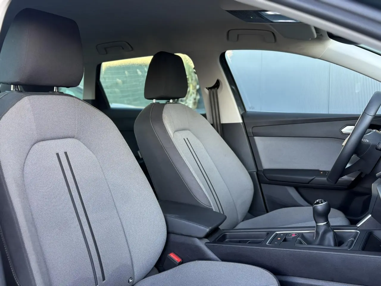 Vue intérieure côté droit sur les sièges gris et la console centrale avec levier de vitesse manuelle de la SEAT LEON ST 2025.
