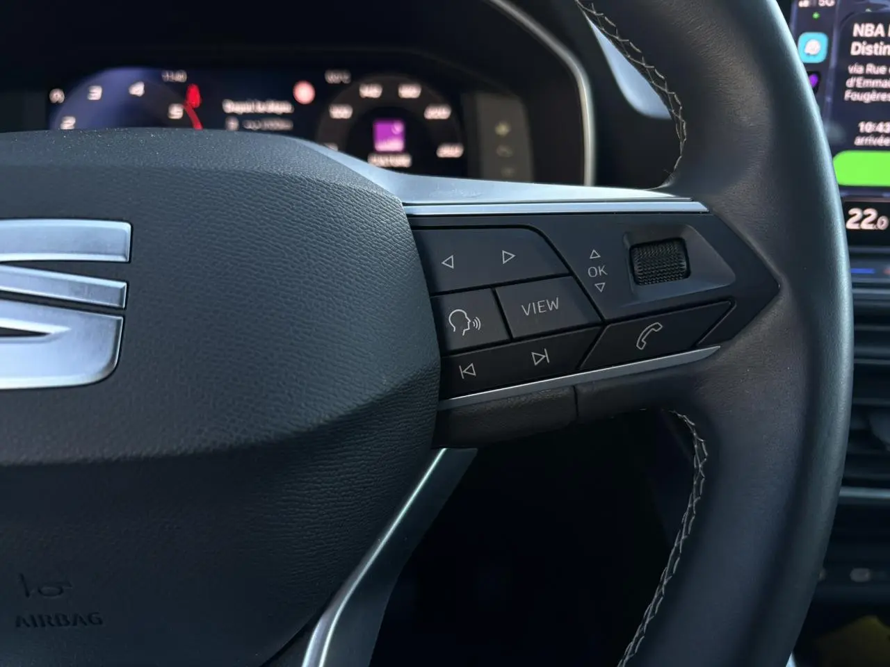 Gros plan sur le volant cuir multifonction côté droit du SEAT LEON ST Bleu Fjord avec commandes intégrées.