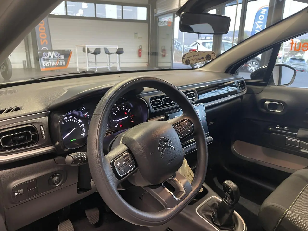 Vue intérieure côté conducteur du tableau de bord et volant noir d'une Citroën C3 2024 avec boîte manuelle.