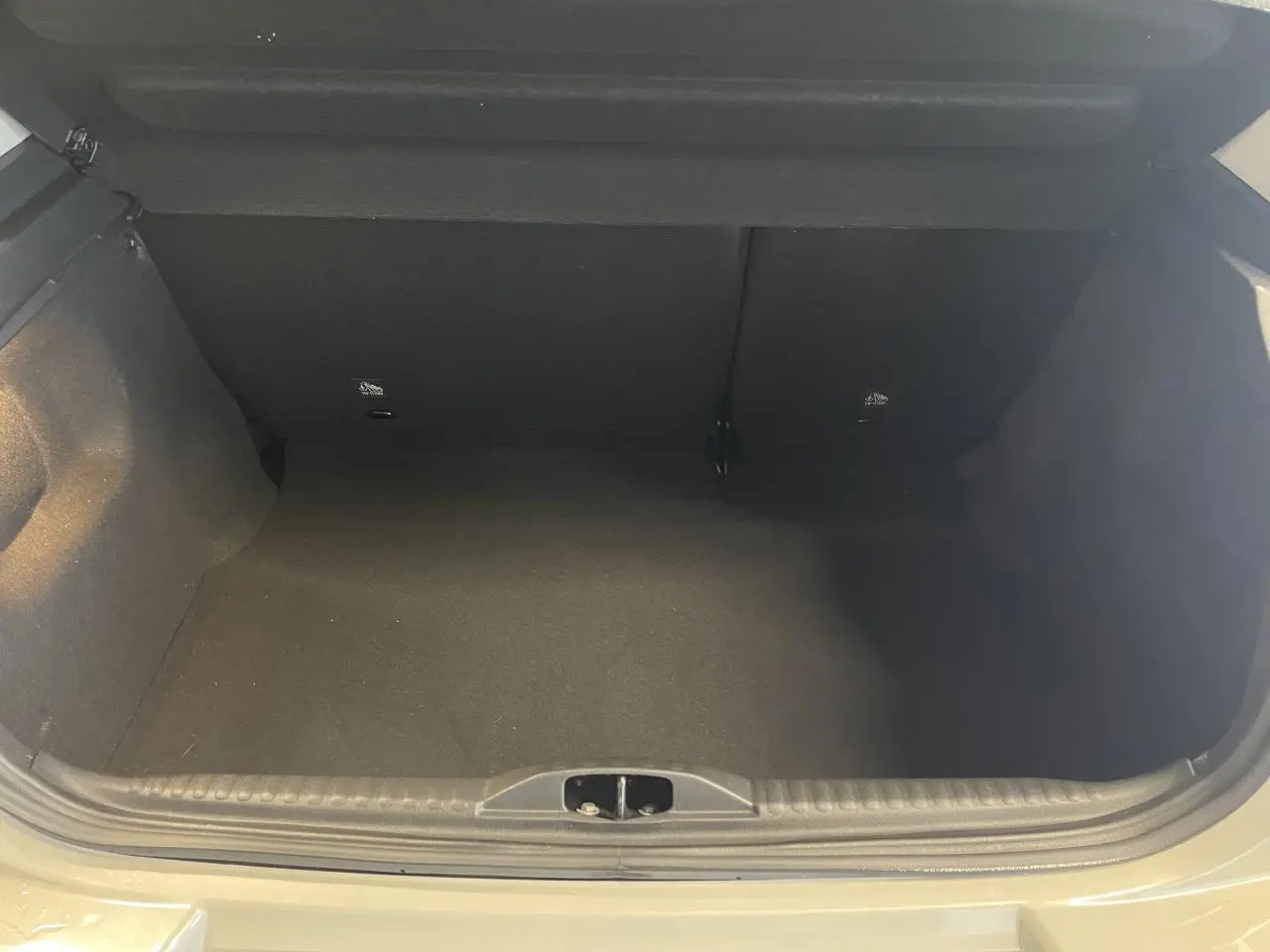 Coffre ouvert vu de face d'une Citroën C3 beige clair 2024, montrant un espace de rangement vide et propre.