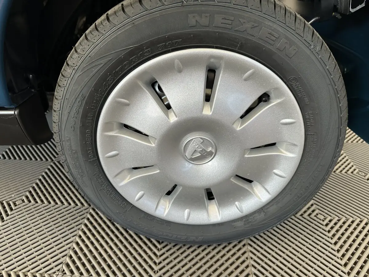 Gros plan sur la roue avant droite avec enjoliveur argenté du véhicule bleu Aixam Ambition 0.5 City Pack 2026.