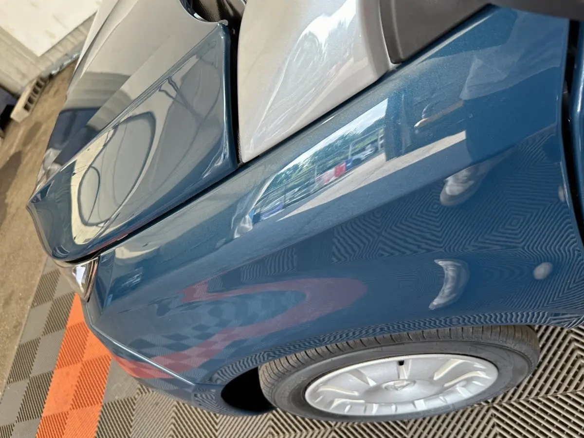 Gros plan sur l’aile avant gauche bleue de l’AIXAM AMBITION 0.5 CITY PACK 2026 avec rétroviseur caméra côté conducteur.