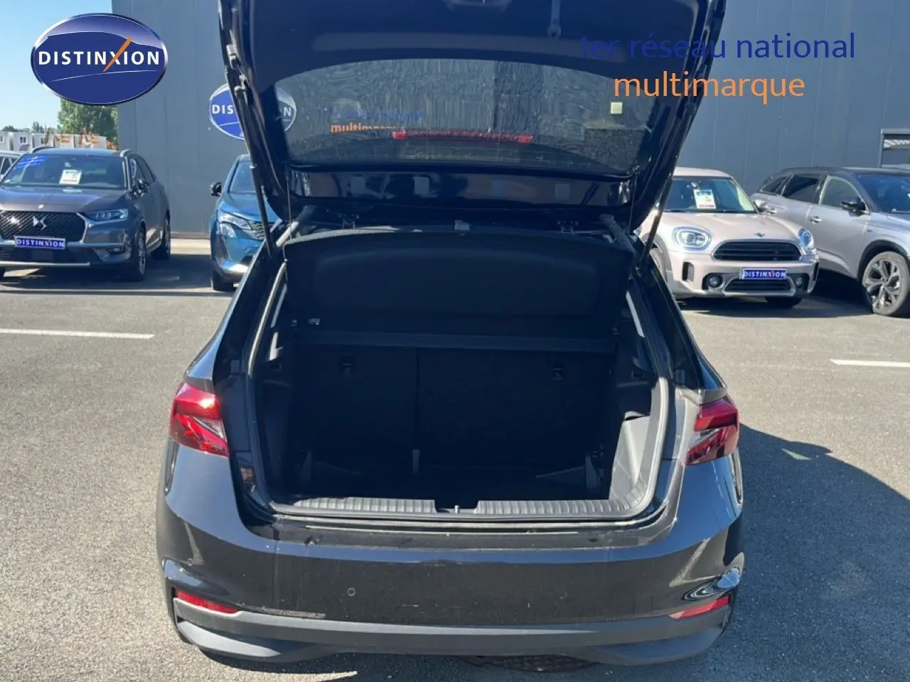 Vue arrière d'une Skoda Fabia 2025 noir magique métal avec coffre ouvert, stationnée en extérieur sur un parking.