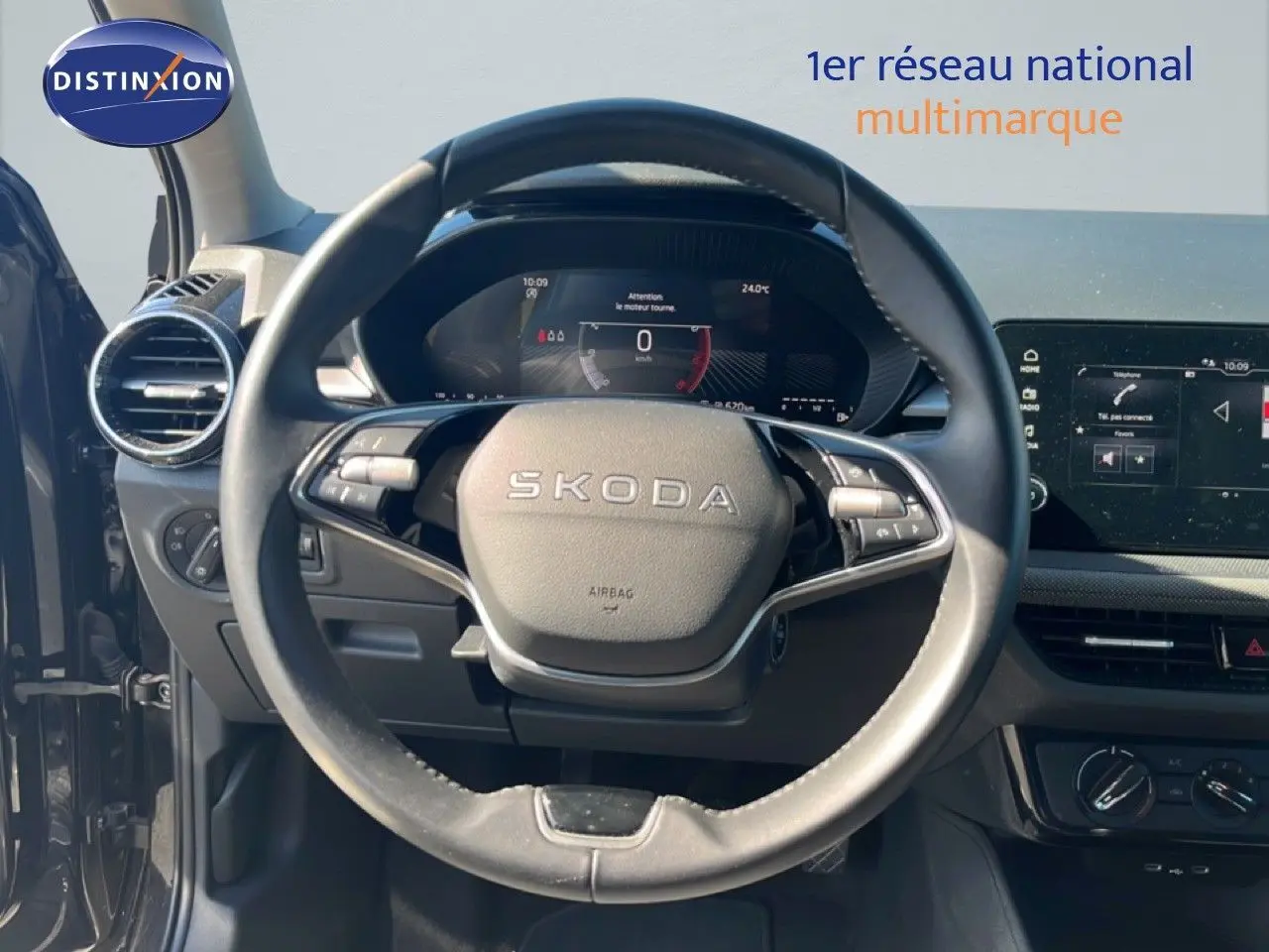 Vue intérieure centrée sur le volant SKODA d'une Fabia 2025 noire, avec tableau de bord numérique et écran tactile visible.