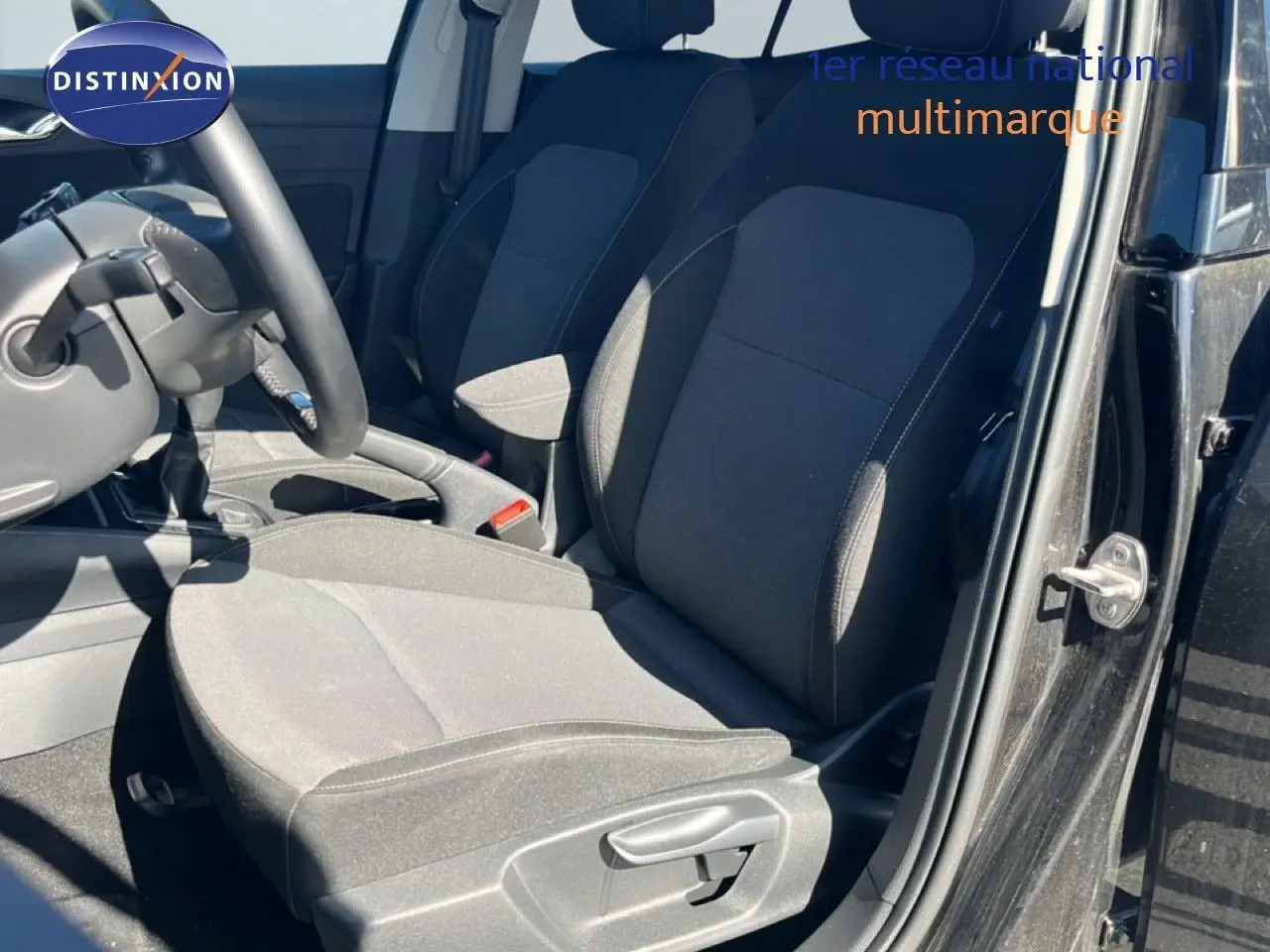 Vue intérieure côté conducteur de la Skoda Fabia 2025 noir magique métal, montrant les sièges en tissu gris foncé et la boîte manuelle.