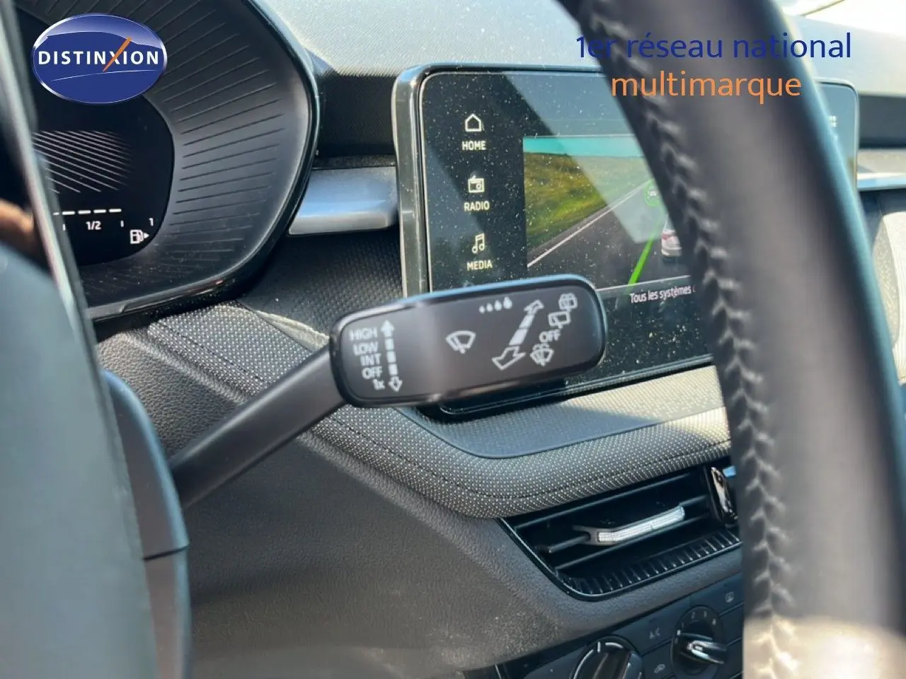 Gros plan sur la commande d’essuie-glace côté gauche du tableau de bord d’une Skoda Fabia noire, avec écran tactile en arrière-plan.