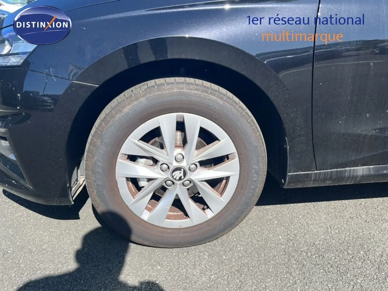 Gros plan sur la roue avant gauche d'une Skoda Fabia noire métal, mettant en valeur la jante en alliage et le logo central.