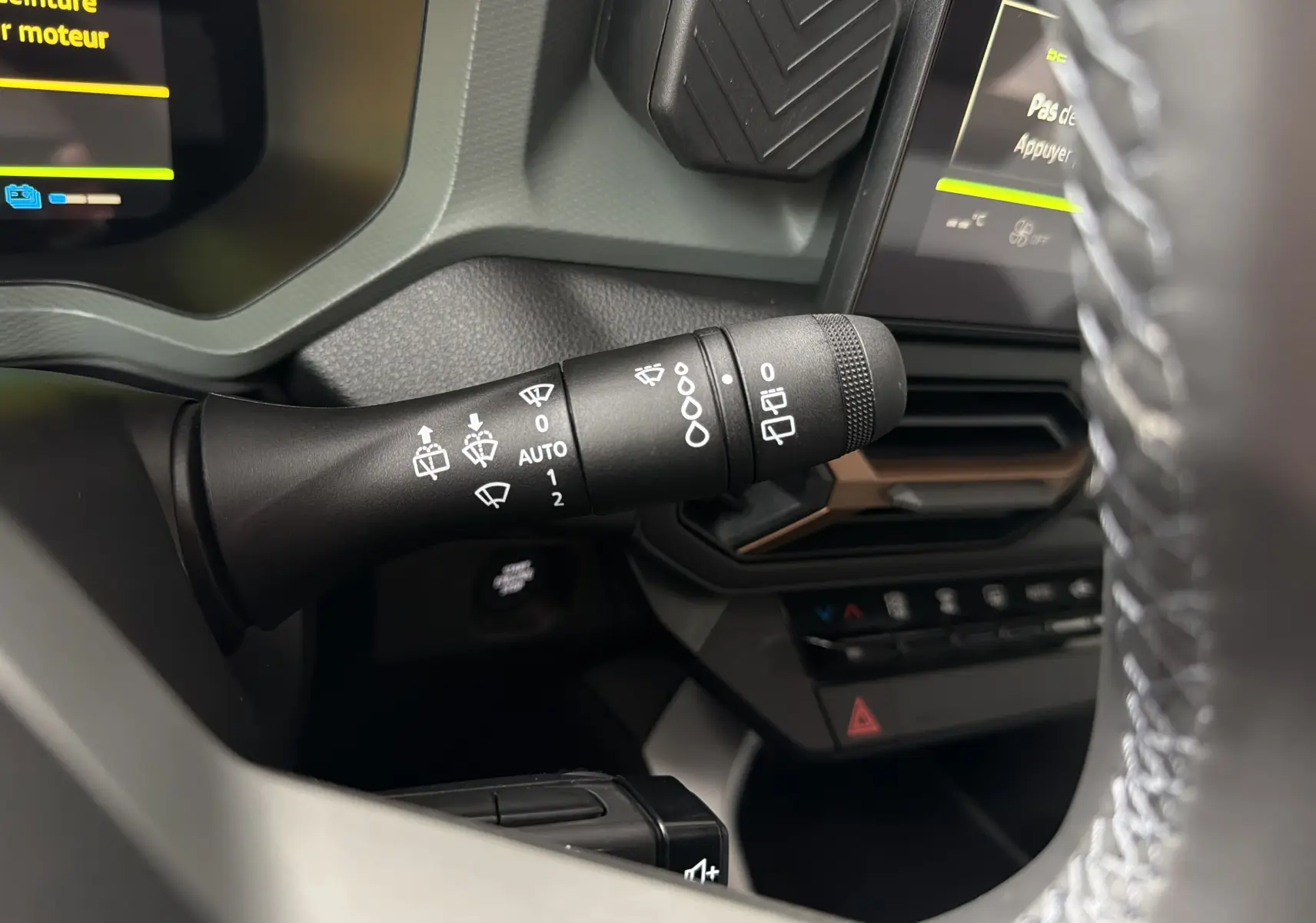 Gros plan sur la commande d’essuie-glace à gauche du volant dans l’habitacle du Dacia Bigster Hybrid 155 bleu indigo.