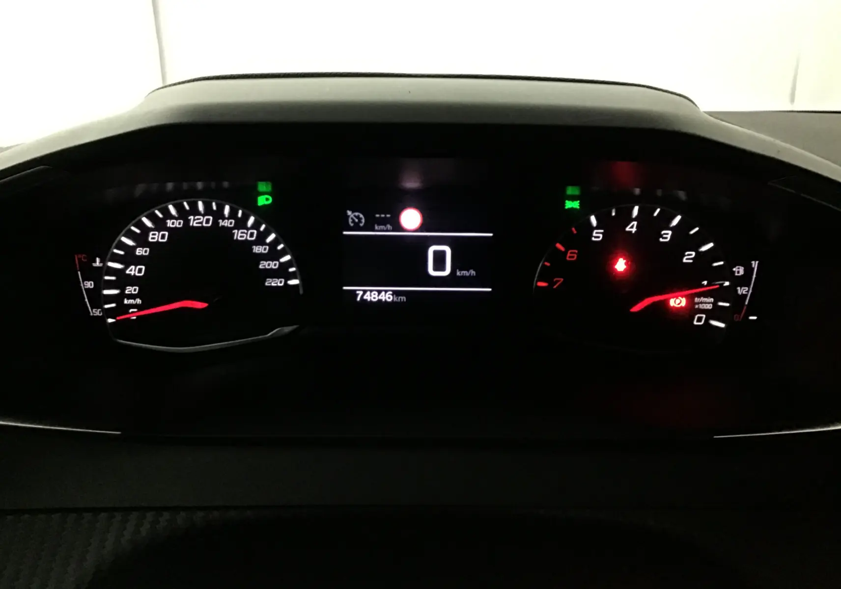 Tableau de bord de Peugeot 208 noir 2022, affichage digital au centre avec compteur vitesse et compte-tours éclairés.