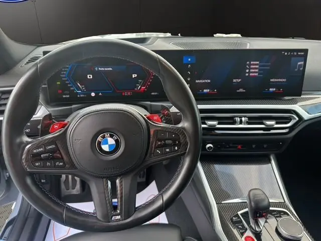 Vue intérieure centrée sur le volant M en cuir avec palettes rouges et tableau de bord numérique d'une BMW M2 G87 2024