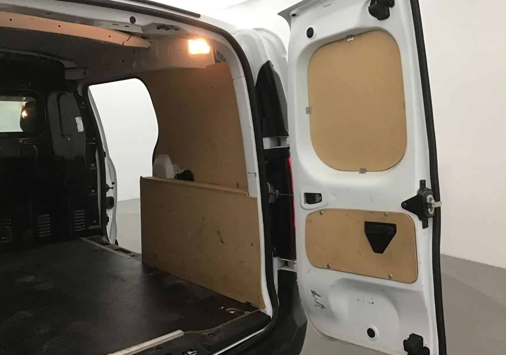 Vue intérieure arrière droite du Renault Express Van blanc 2023, montrant l'espace de chargement avec panneaux en bois et éclairage intérieur.
