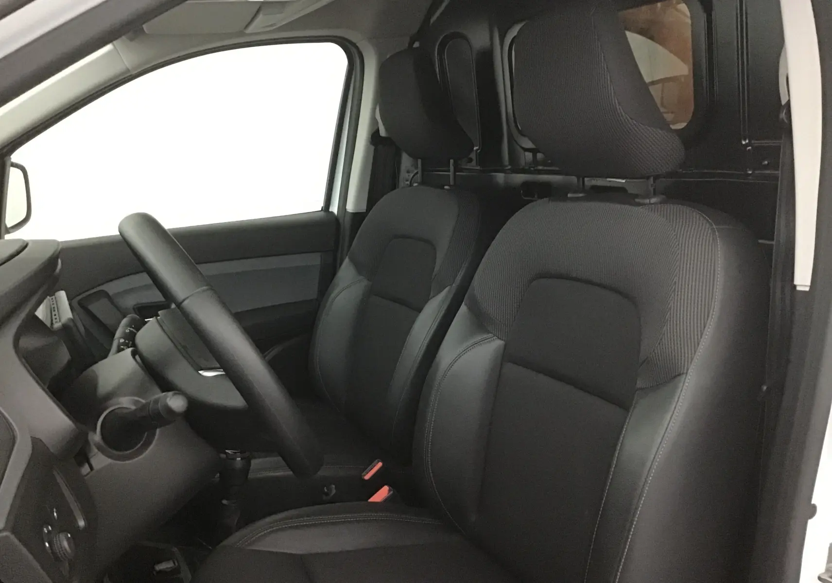 Vue intérieure côté conducteur du Renault Express Van 2023 blanc, sièges noirs et cloison séparatrice visible.