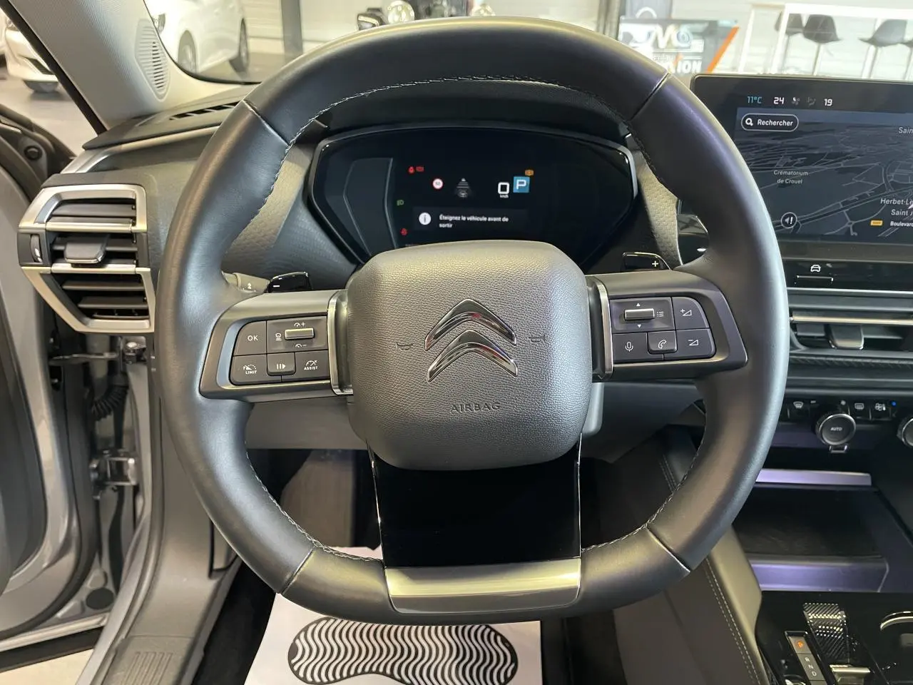 Vue centrée sur le volant cuir noir du Citroën C5 X gris foncé 2024 avec tableau de bord numérique et écran tactile.
