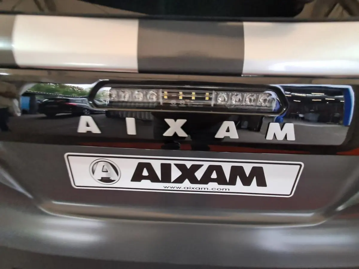 Gros plan sur la calandre avant grise claire de l'Aixam Ambition 2024 avec logo et feu LED intégré.