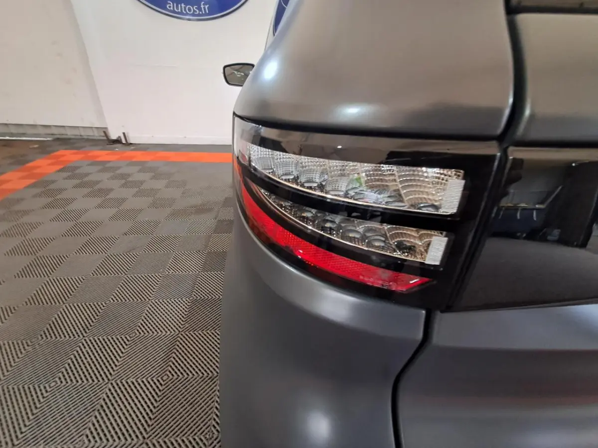 Gros plan sur le feu arrière droit gris clair de l’Aixam Ambition 2024 avec finition GT et jantes noires diamantées visibles.