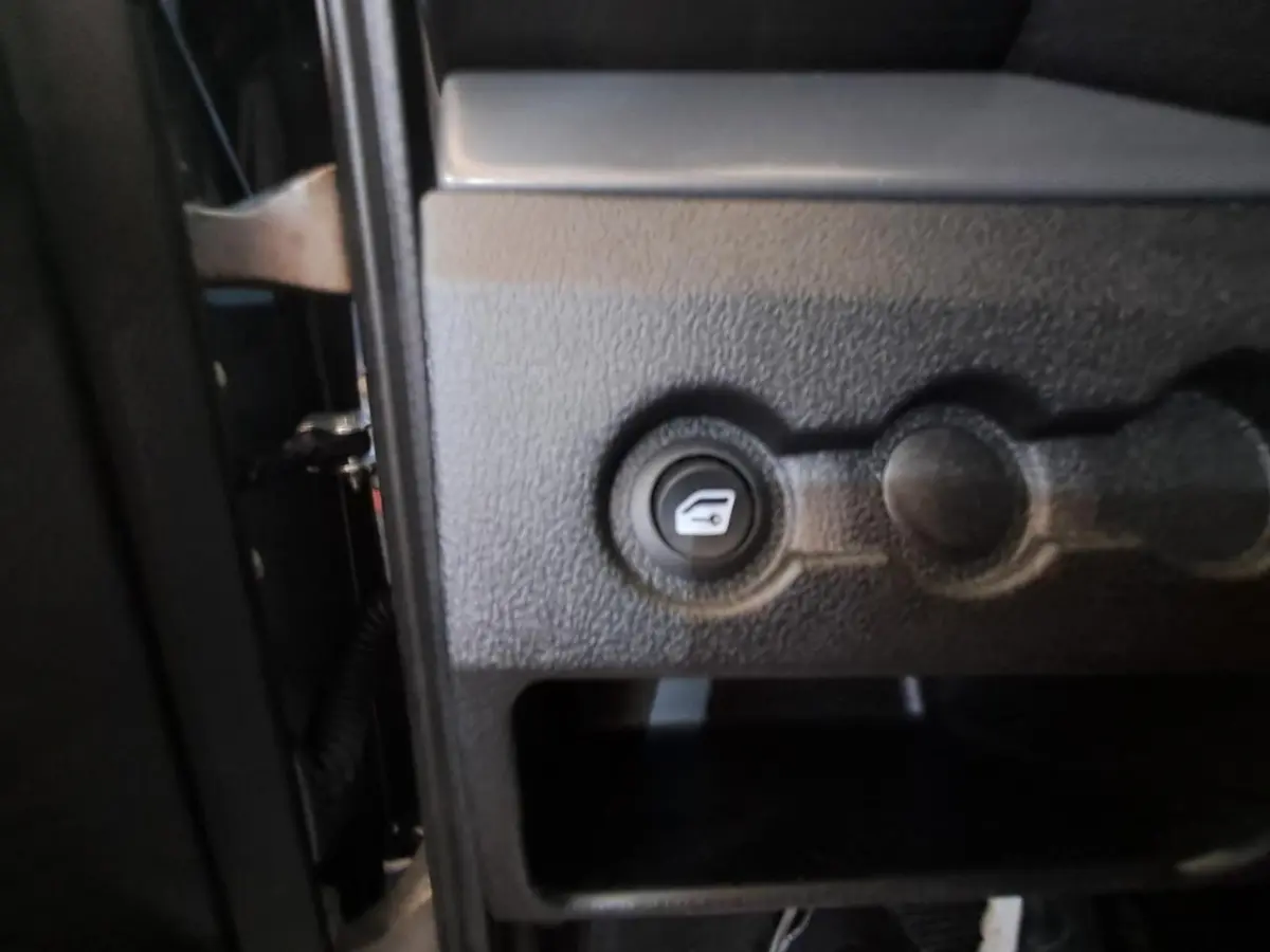 Gros plan sur le bouton d'ouverture du coffre côté conducteur de l'AIXAM AMBITION gris clair 2024.