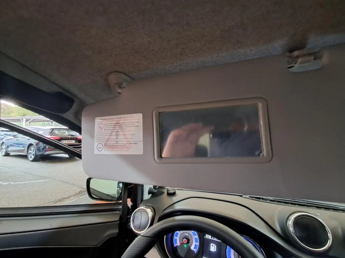 Vue intérieure côté conducteur de l’AIXAM AMBITION gris clair 2024, avec tableau de bord et pare-soleil équipé d’un miroir.