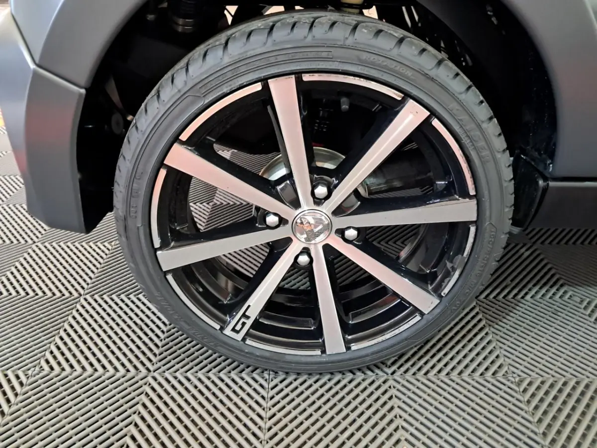 Gros plan sur la jante alliage 16’’ noires diamantées avec logo GT de l’Aixam Ambition gris clair 2024.