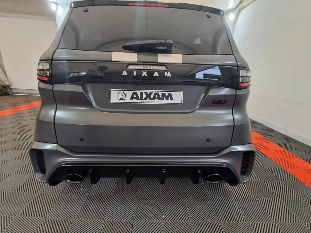 Vue arrière d'une Aixam Ambition gris clair avec logo GTO, double sortie d'échappement et bande décorative blanche sur le toit.