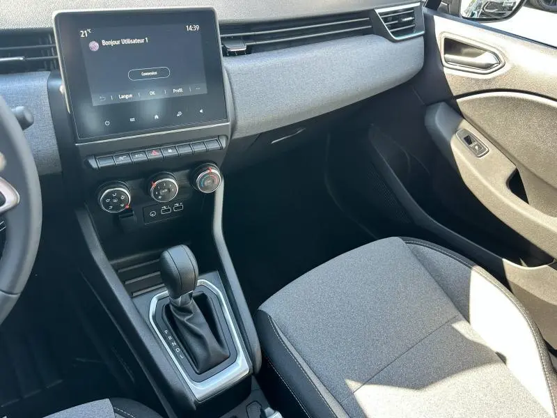 Intérieur avant droit de Renault Clio 2025 gris Rafale, tableau de bord avec écran tactile et levier de boîte manuelle.