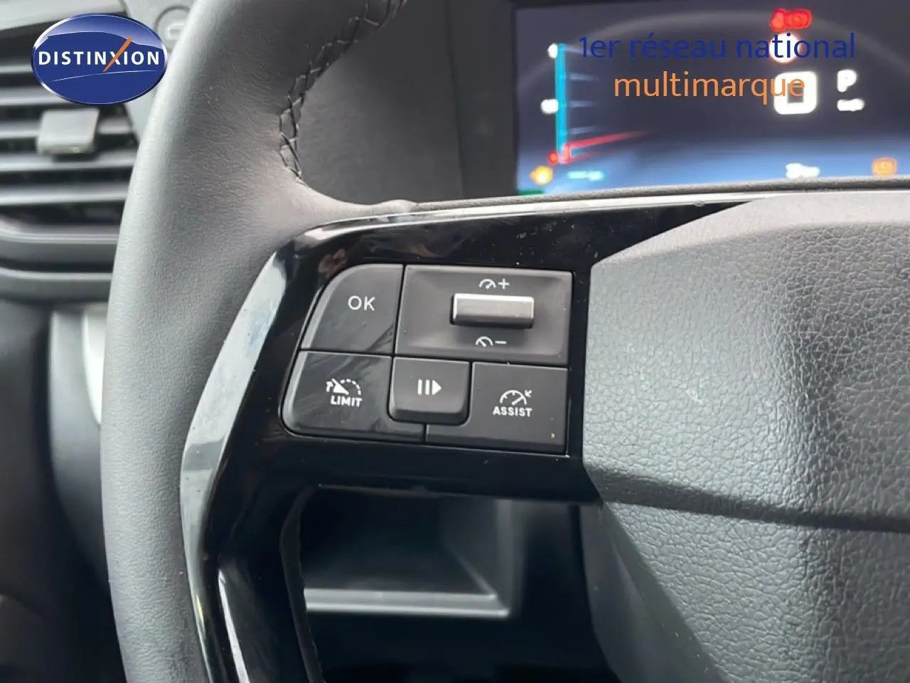 Gros plan sur les commandes au volant en cuir noir du Citroën Jumpy L3 gris titane, avec affichage numérique en arrière-plan.