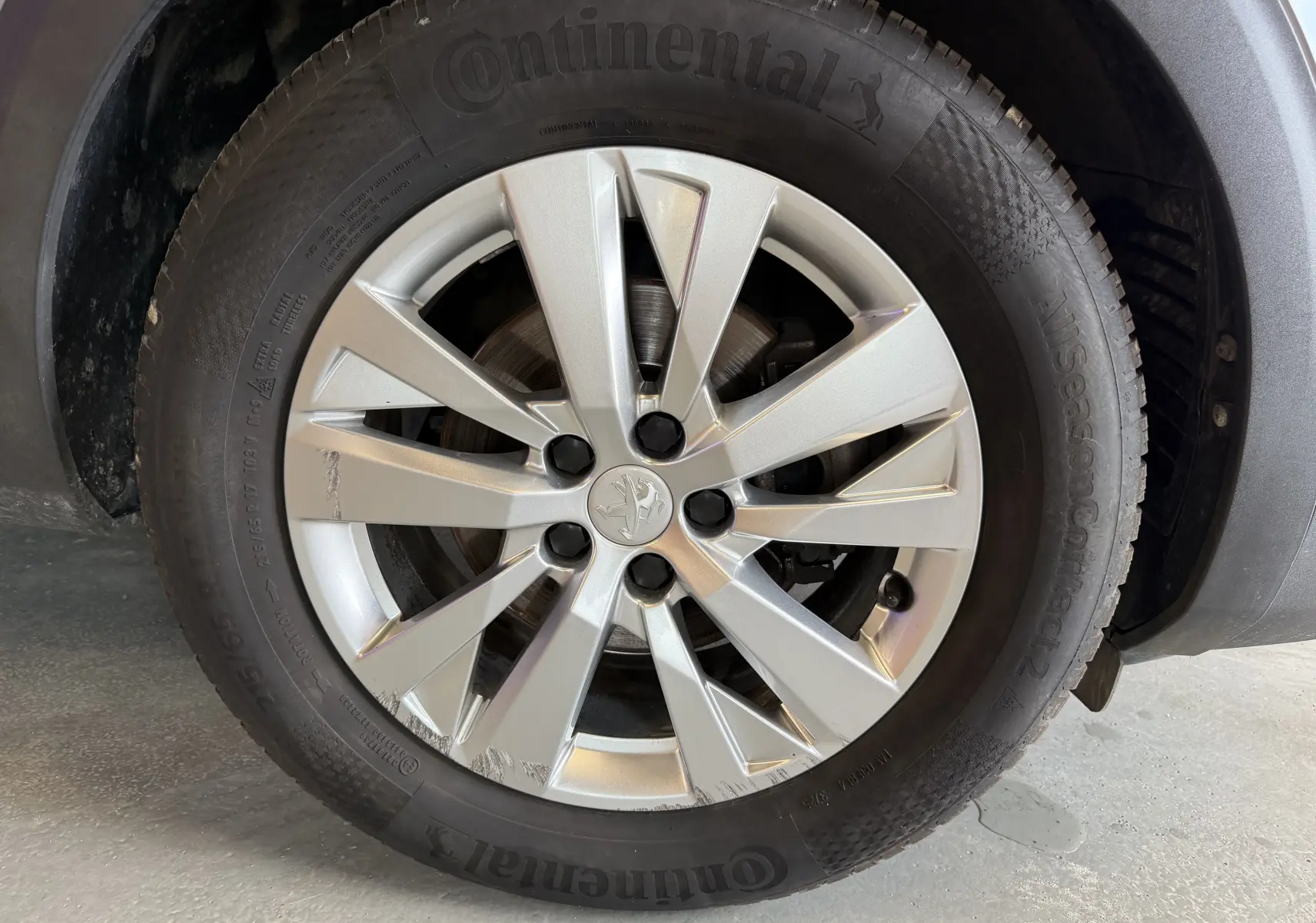 Gros plan sur la roue avant gauche gris métallisé du Peugeot 5008 1.5 BlueHDi 130 Allure avec jante alliage marquée.