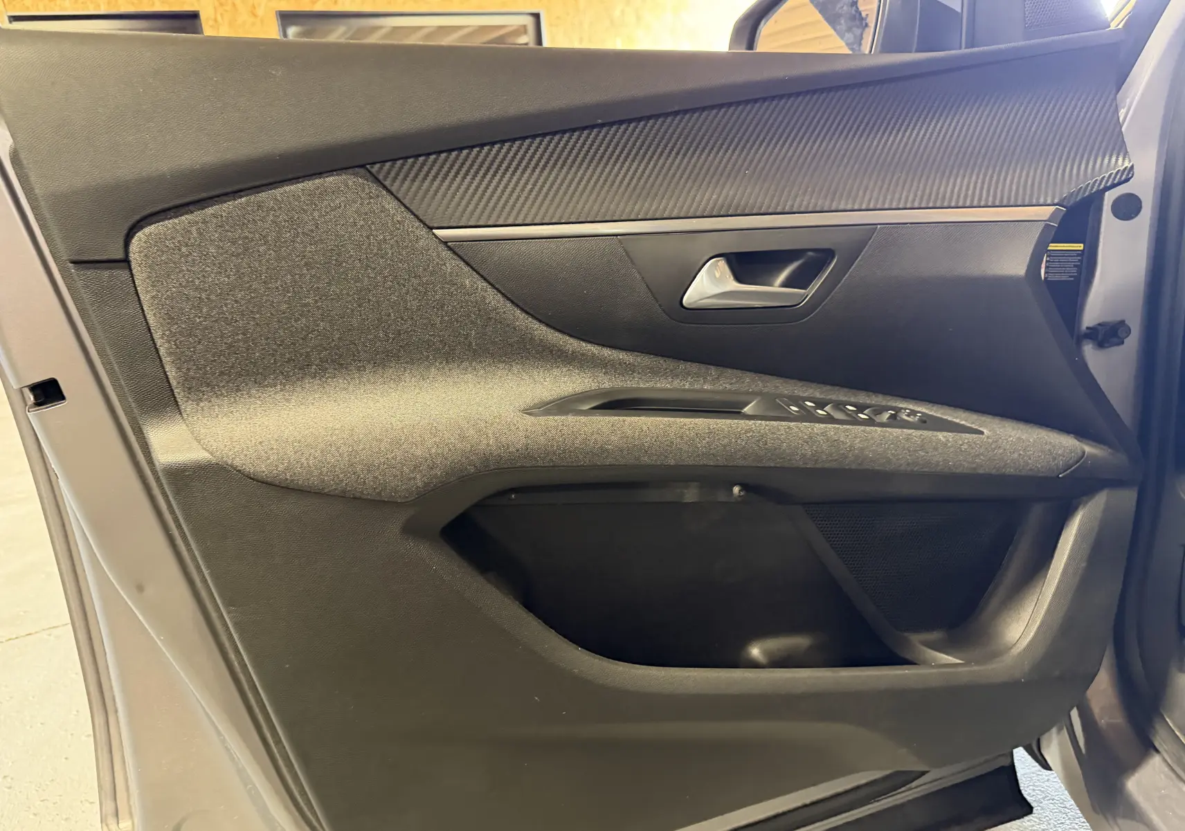 Vue rapprochée de la porte avant gauche grise du Peugeot 5008 1.5 BlueHDi, avec garniture noire et commandes de vitres.