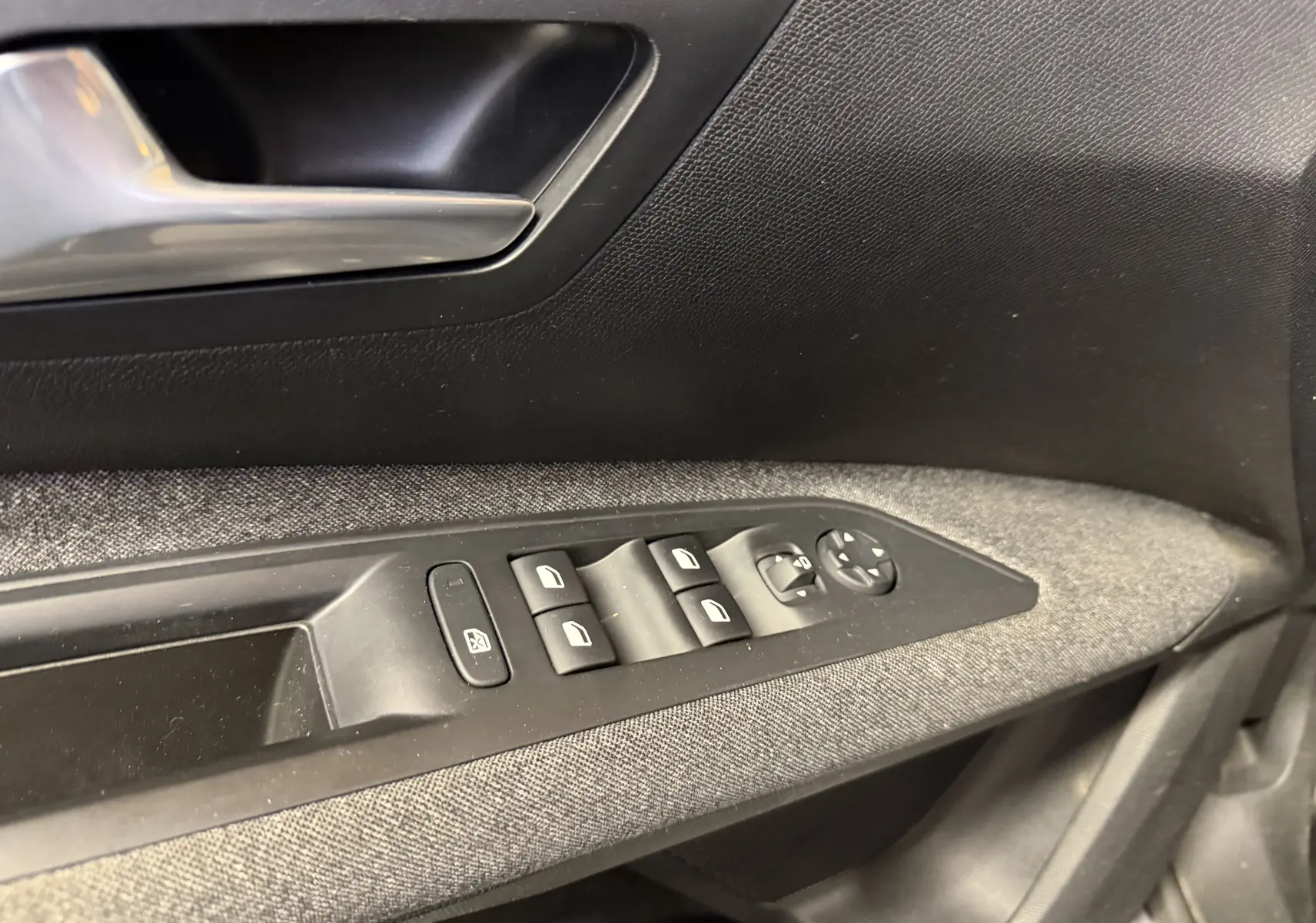 Détail de la commande des vitres et rétroviseurs côté conducteur du Peugeot 5008 gris, intérieur tissu noir.