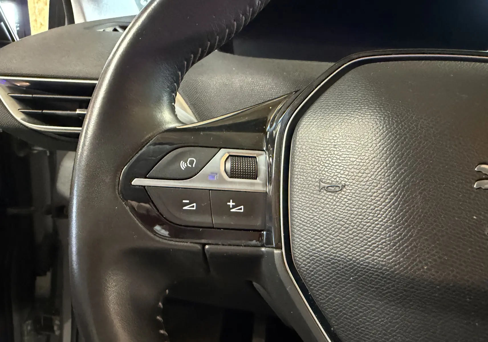 Gros plan sur le volant noir du Peugeot 5008 1.5 BlueHDi 130, avec commandes audio intégrées à gauche.