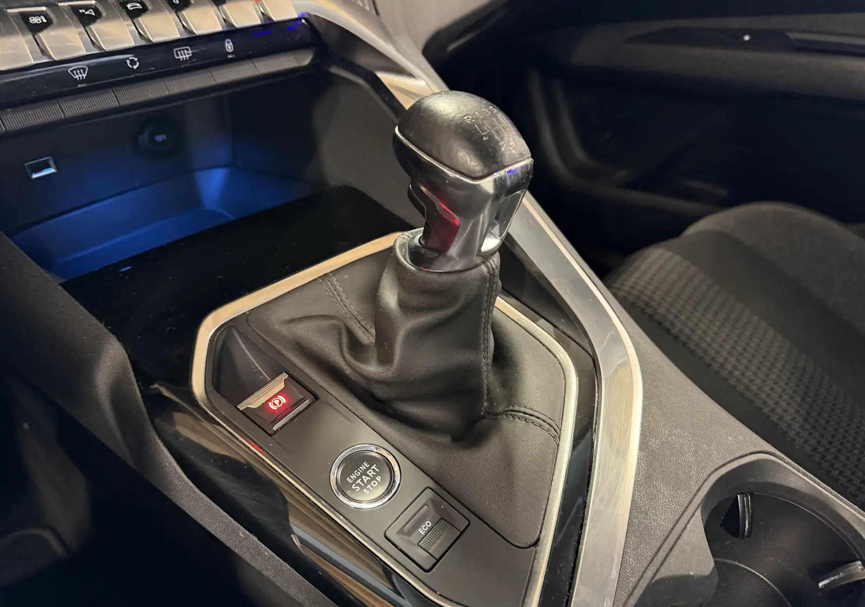 Gros plan sur le levier de vitesses manuel noir et la console centrale du Peugeot 5008 gris, avec bouton start/stop et frein à main électrique.