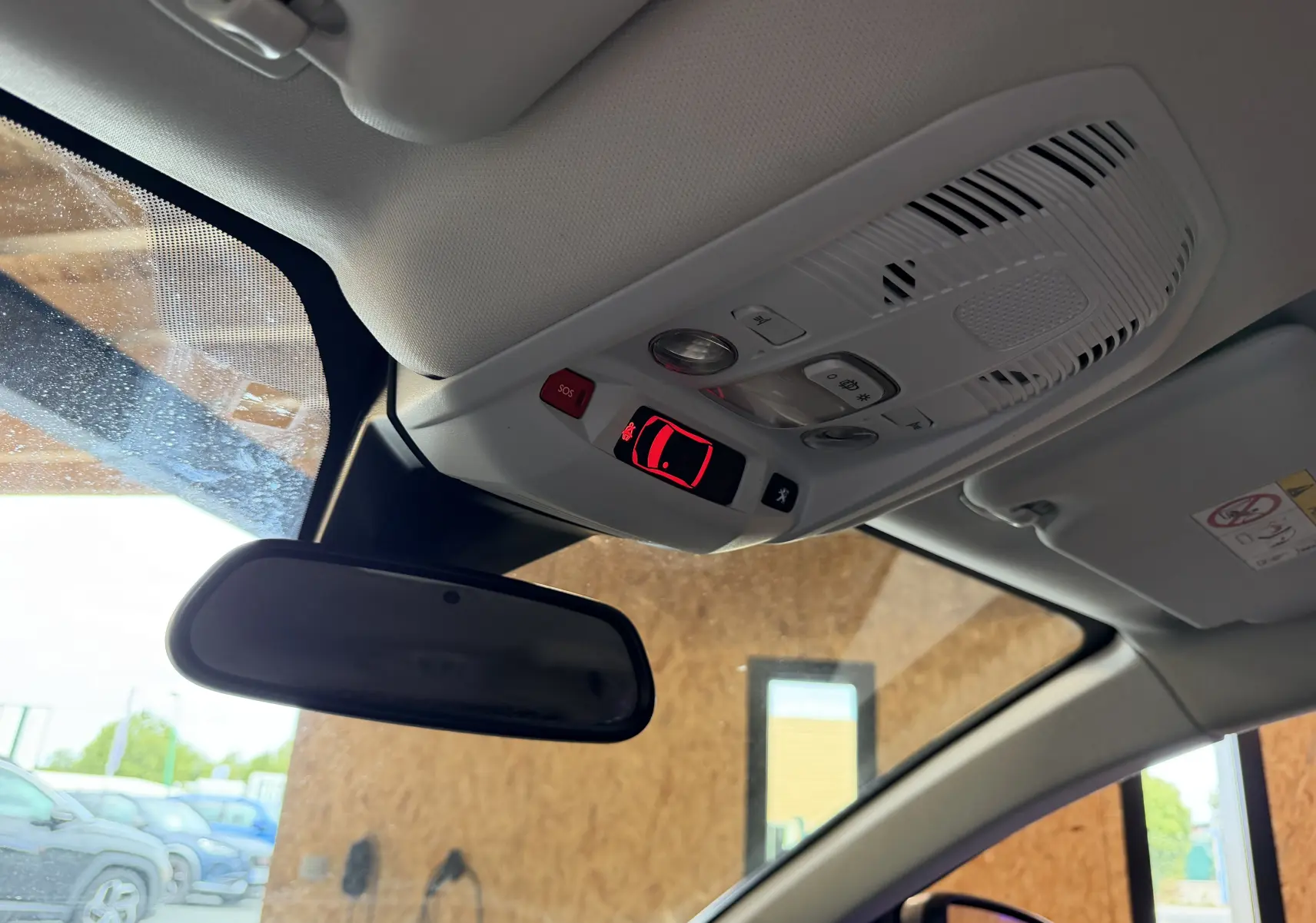 Vue intérieure du plafond avant du Peugeot 5008 gris, avec commandes d’éclairage et rétroviseur central visible.