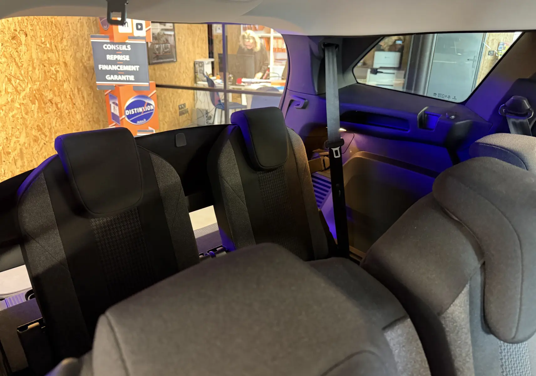 Vue intérieure arrière du Peugeot 5008 gris, montrant les sièges en tissu noir de la troisième rangée et la ceinture de sécurité côté droit.