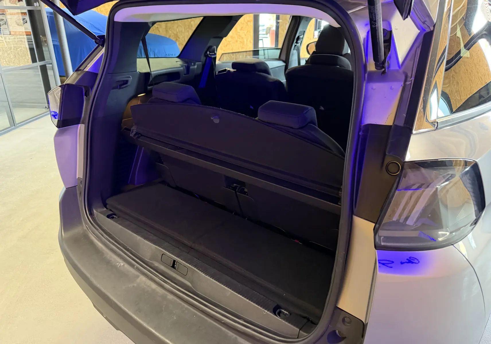 Coffre ouvert vu de l'arrière droit d'un Peugeot 5008 gris 2021, montrant la banquette arrière et l'intérieur noir.
