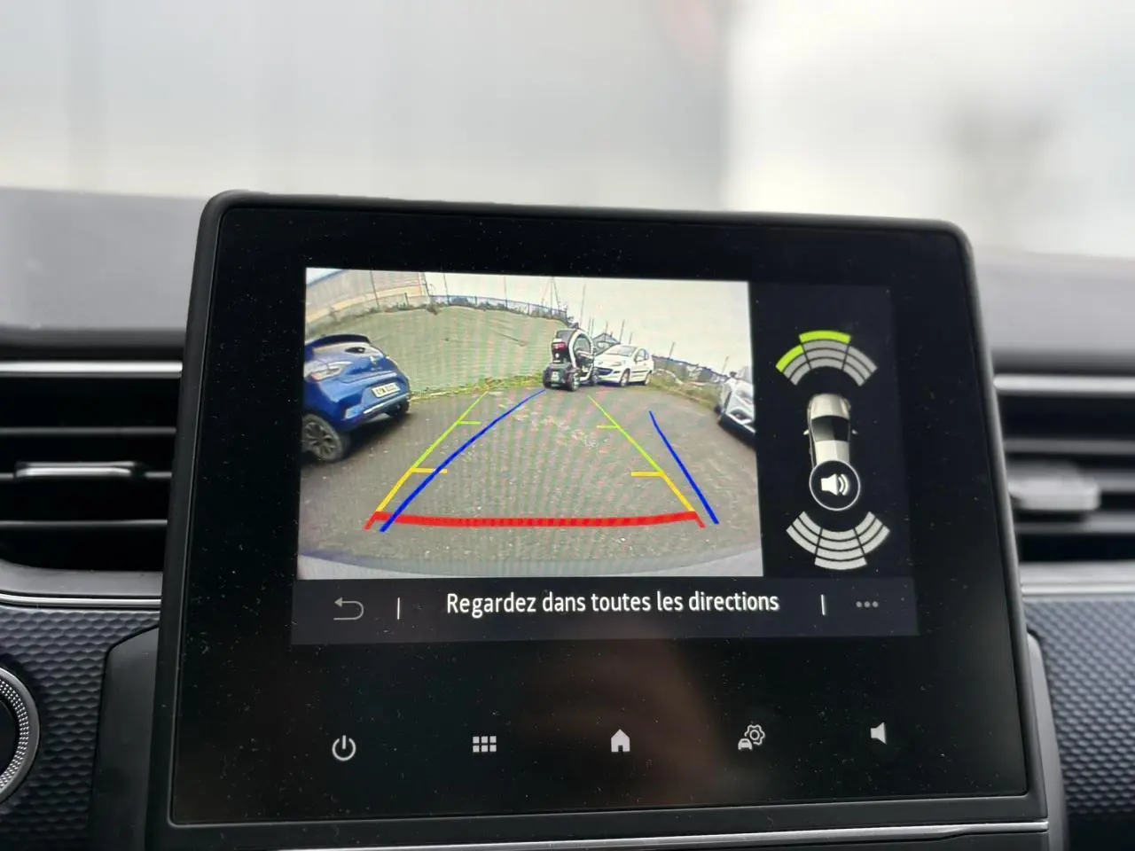 Écran tactile intérieur montrant la caméra de recul avec vue arrière et aides au stationnement du Renault Arkana bleu Zanzibar.