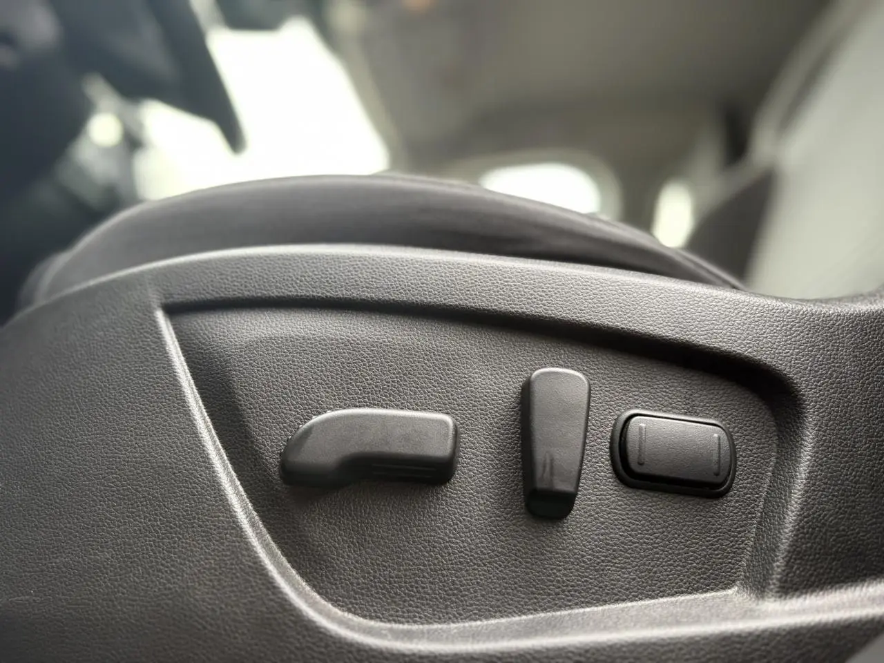 Gros plan sur les commandes électriques du siège conducteur d’un Renault Arkana 2025, intérieur noir.