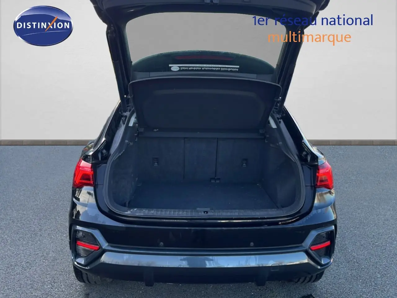 Vue arrière d’un Audi Q3 Sportback noir 2022 avec coffre ouvert et feux arrière allumés.