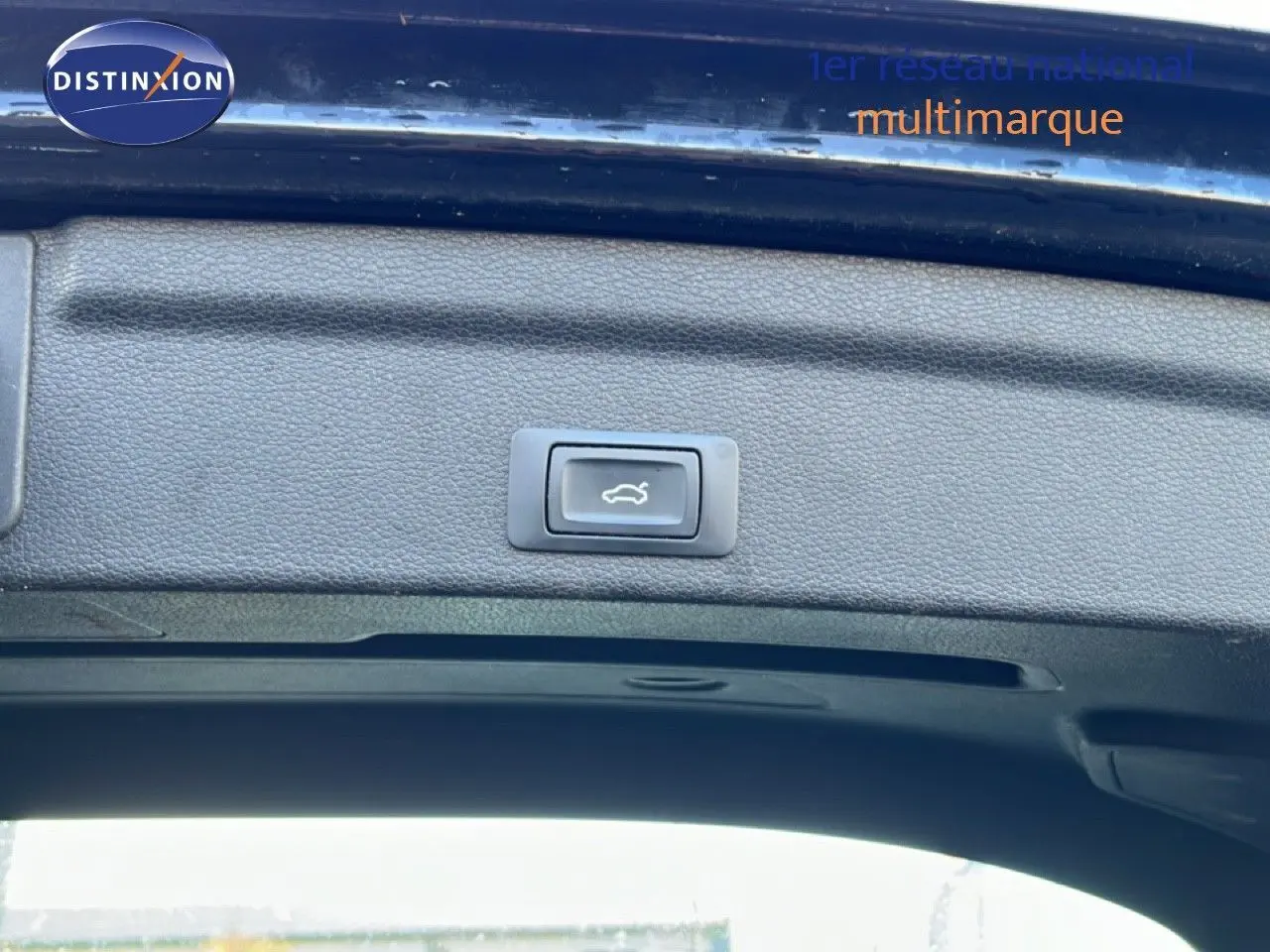 Bouton d'ouverture électrique du coffre sur la partie intérieure du hayon d'un Audi Q3 Sportback noir, vue en contre-plongée.