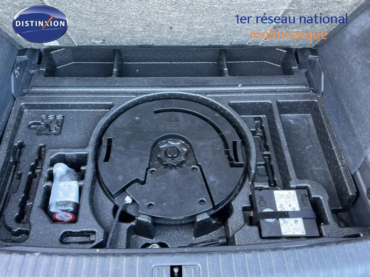 Coffre ouvert montrant le rangement sous plancher avec kit de réparation et emplacement roue de secours du Audi Q3 Sportback noir.