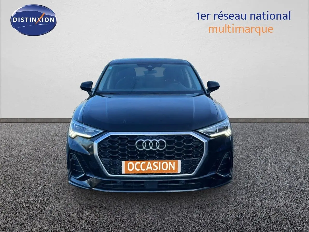 Vue frontale d'un Audi Q3 Sportback 35 TDI 150 S-Line noir avec calandre hexagonale et phares LED allumés.