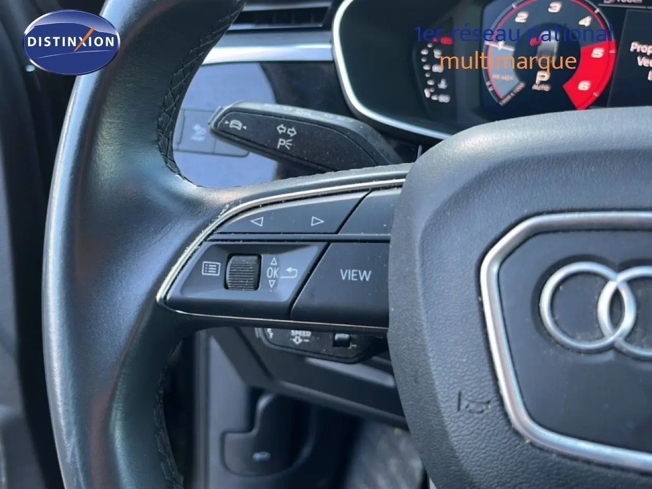 Gros plan sur le volant noir d’un Audi Q3 Sportback 2022, montrant les commandes multifonctions côté gauche et le logo Audi central.