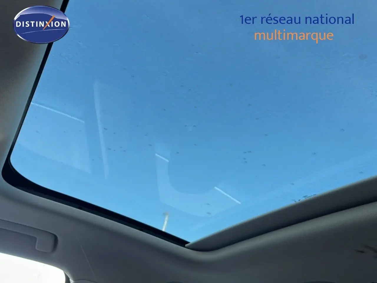 Toit panoramique en verre vu de l'intérieur de l'Audi Q3 Sportback noir, laissant entrevoir un ciel bleu.