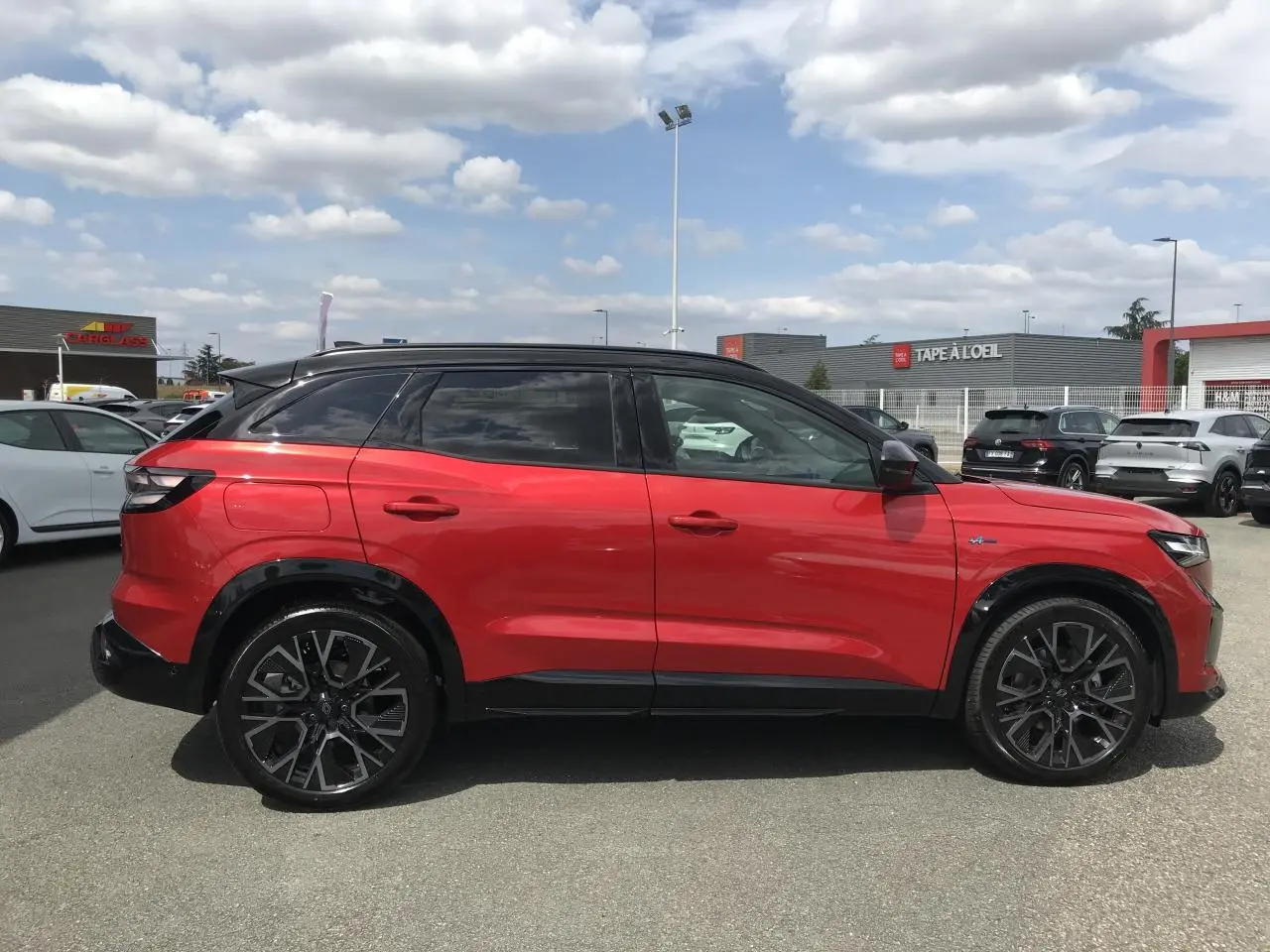 Vue de profil côté gauche d'un Renault Austral 2025 bi-ton rouge et noir avec jantes alliage noires diamantées.