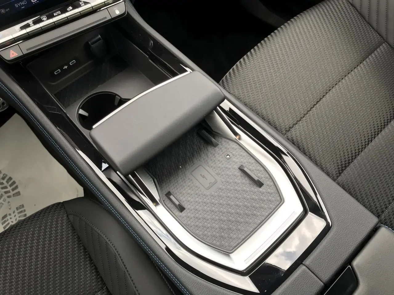 Vue plongeante sur la console centrale noire du Renault Austral hybride avec chargeur smartphone à induction et sellerie tissu noire.