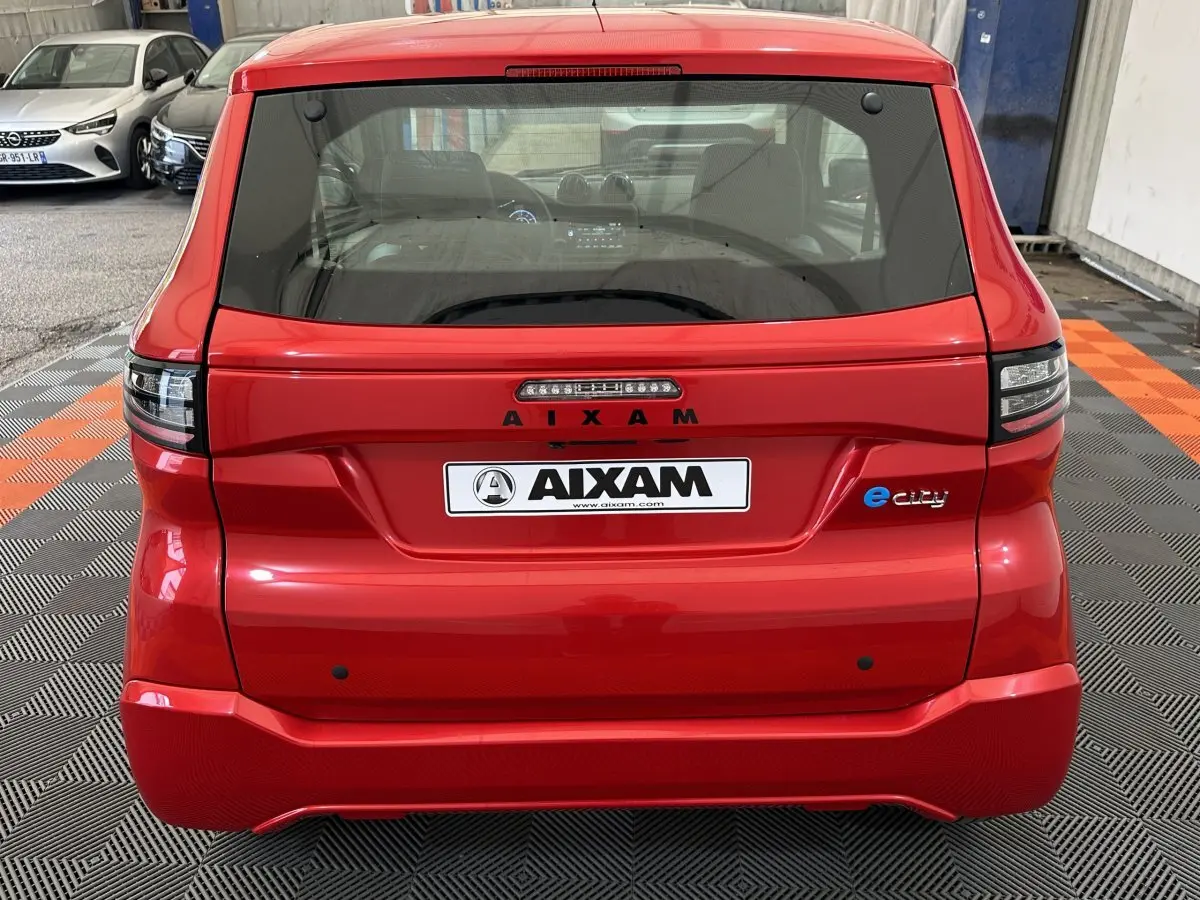 Vue arrière d'une Aixam Ambition E City Pack rouge 2026 avec logo e-city et feux arrière modernes.