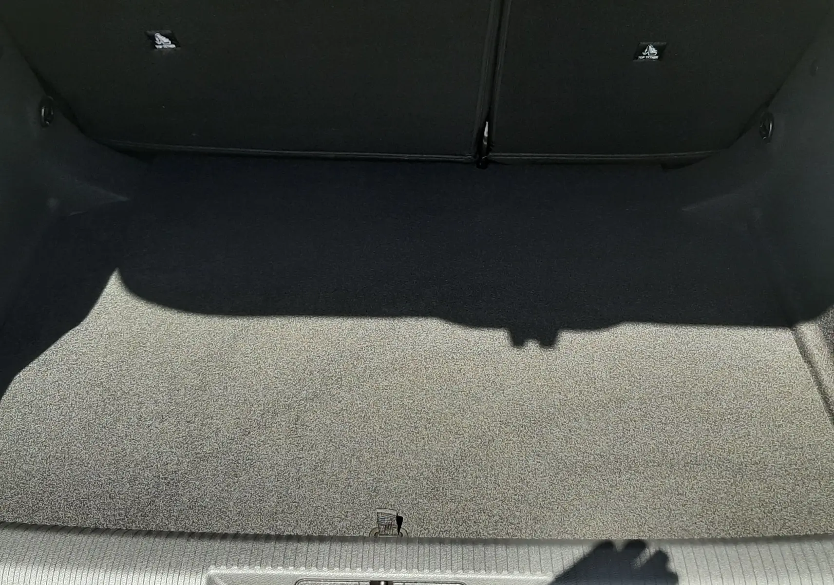 Coffre ouvert vu de dessus d'une Peugeot 308 gris selenium, montrant un espace de chargement propre et vide.