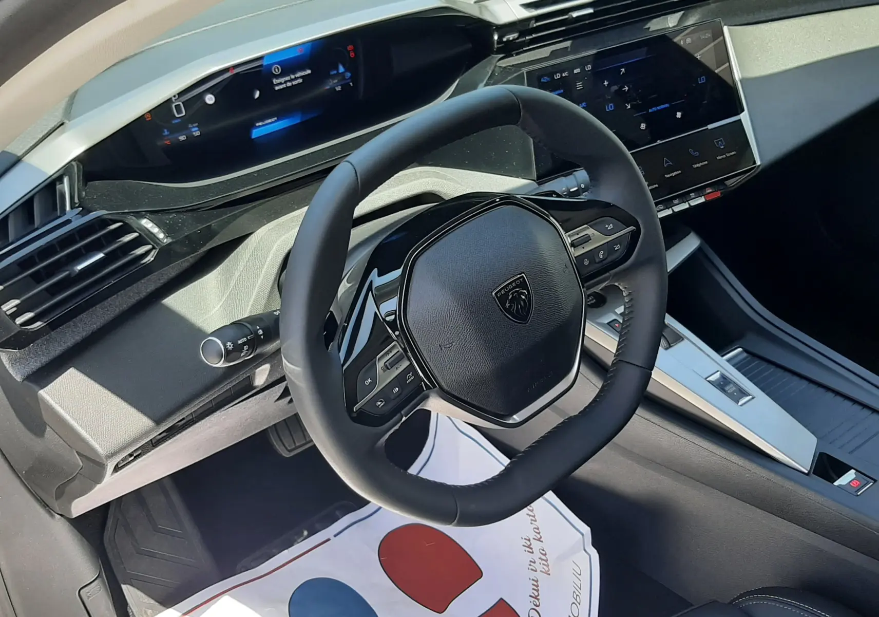 Vue intérieure côté conducteur du tableau de bord et volant noir de la Peugeot 308 gris selenium, avec écran tactile et instrumentation digitale.