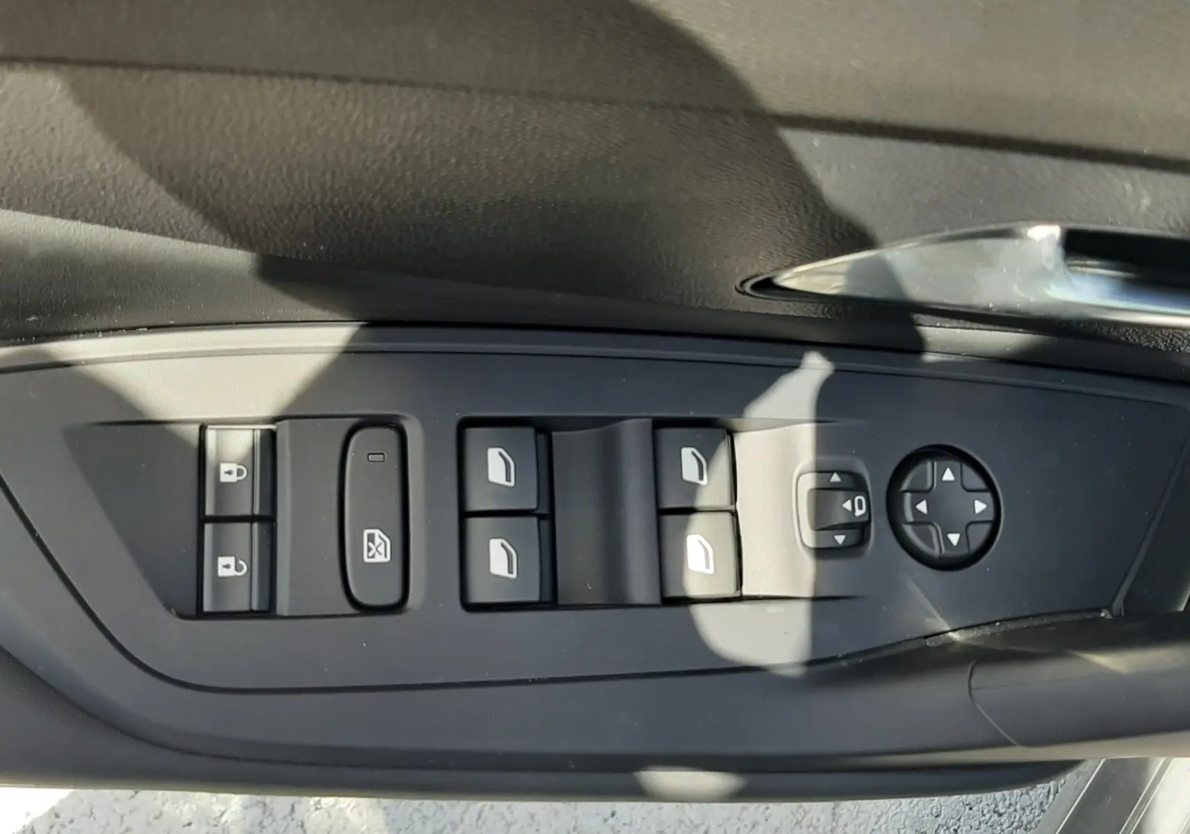 Vue rapprochée des commandes de lève-vitres et rétroviseurs sur la porte côté conducteur d'une Peugeot 308 gris selenium.