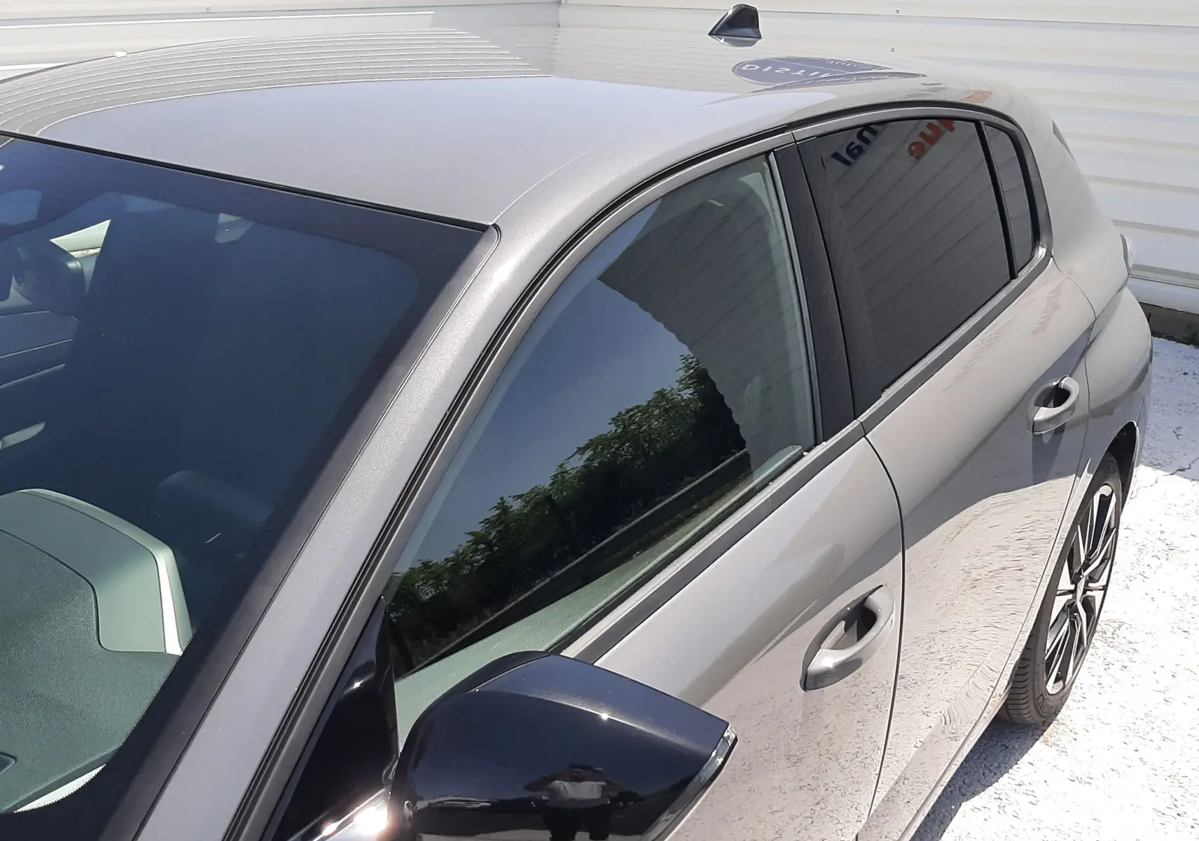 Vue 3/4 avant droit d’une Peugeot 308 gris sélénium avec rétroviseur noir brillant et jantes alliage visibles.